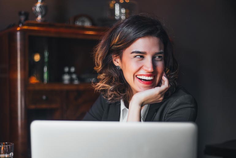 woman smiles with veneers while working